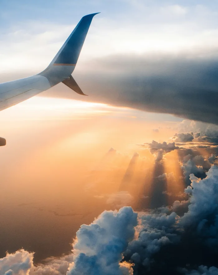 Aeroplane wing above sunlit clouds.