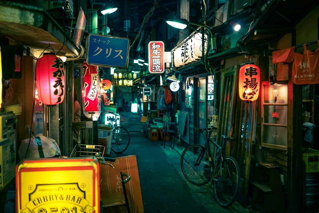 Neon-lit alleyway in Tokyo, Japan, featuring cozy izakayas and vibrant street signs.