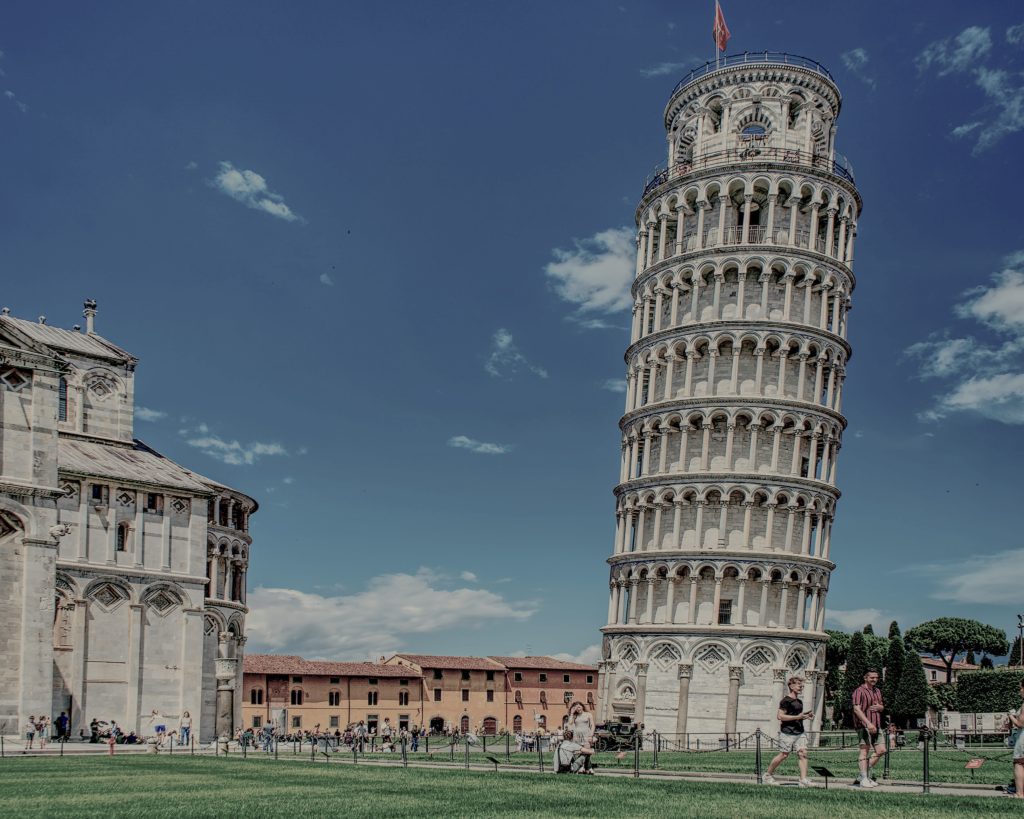 The Leaning Tower of Pisa under a clear blue sky, surrounded by tourists exploring the iconic landmark in Italy.