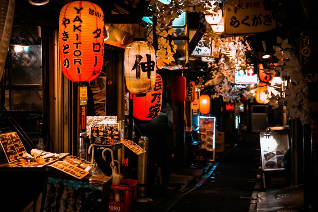 Tokyo's vibrant Omoide Yokocho at night, illuminated by red lanterns and offering diverse street food stalls.