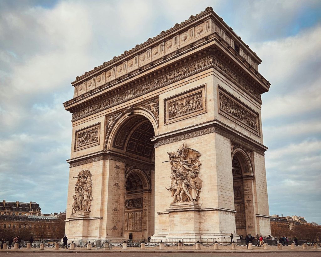 Arc de Triomphe in Paris, France, with detailed sculptures and a dramatic sky backdrop.