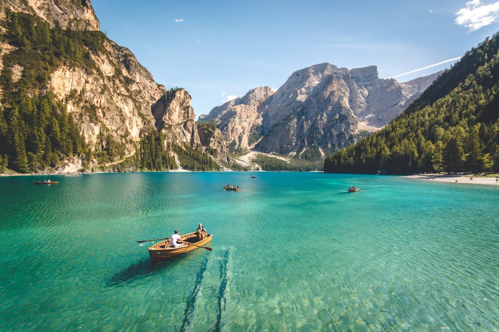 Rowboats on the clear turquoise waters of Lake Braies in the Dolomites, surrounded by majestic alpine mountains.