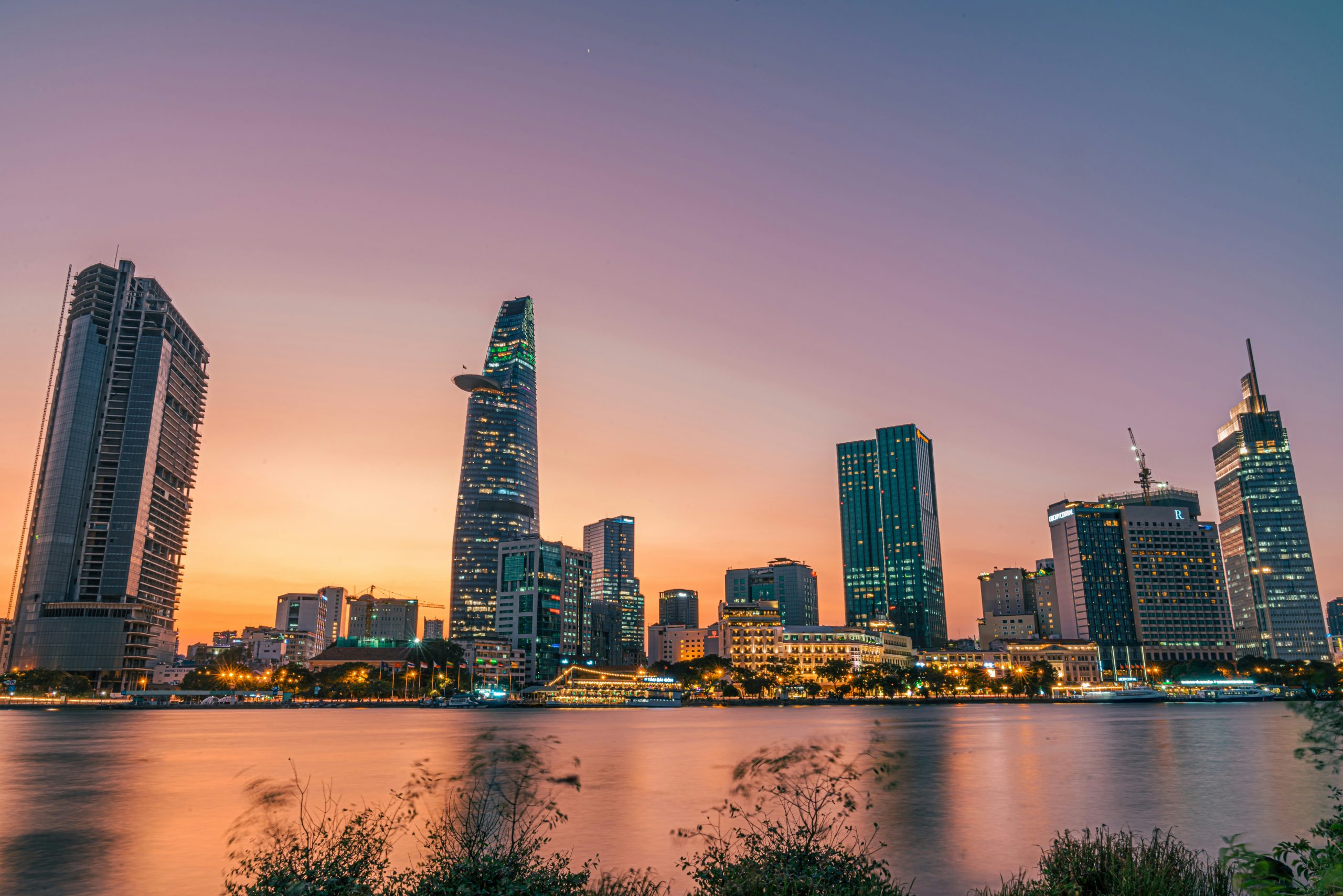 Ho Chi Minh City skyline at dusk, reflecting vibrant hues over the Saigon River, Vietnam.