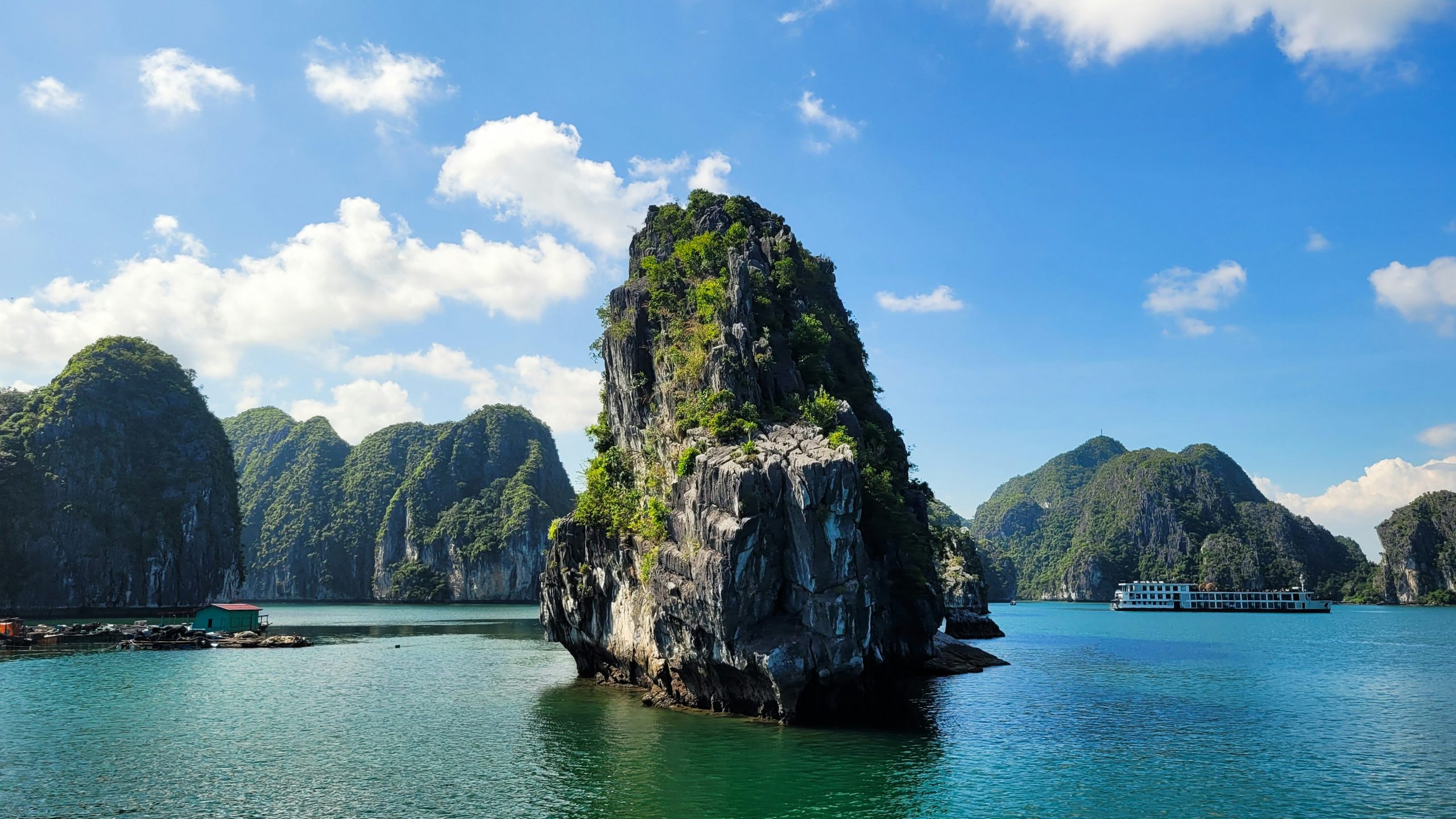 Dramatic limestone karsts rise from turquoise waters in Halong Bay, Vietnam, under a bright blue sky.